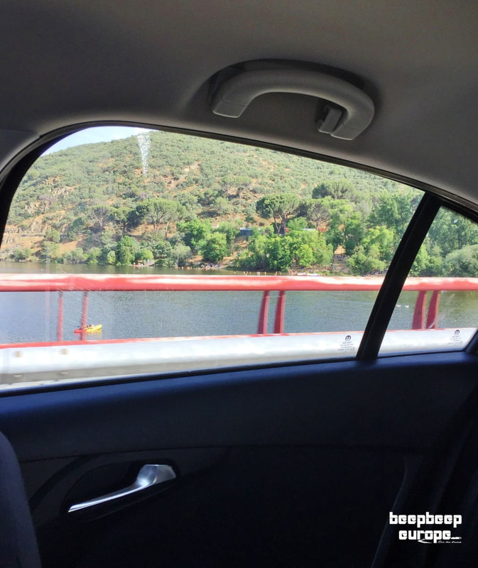 Inside a moving car, through the window the views of the river and the green tree-filled hills surrounding it are breathtaking.